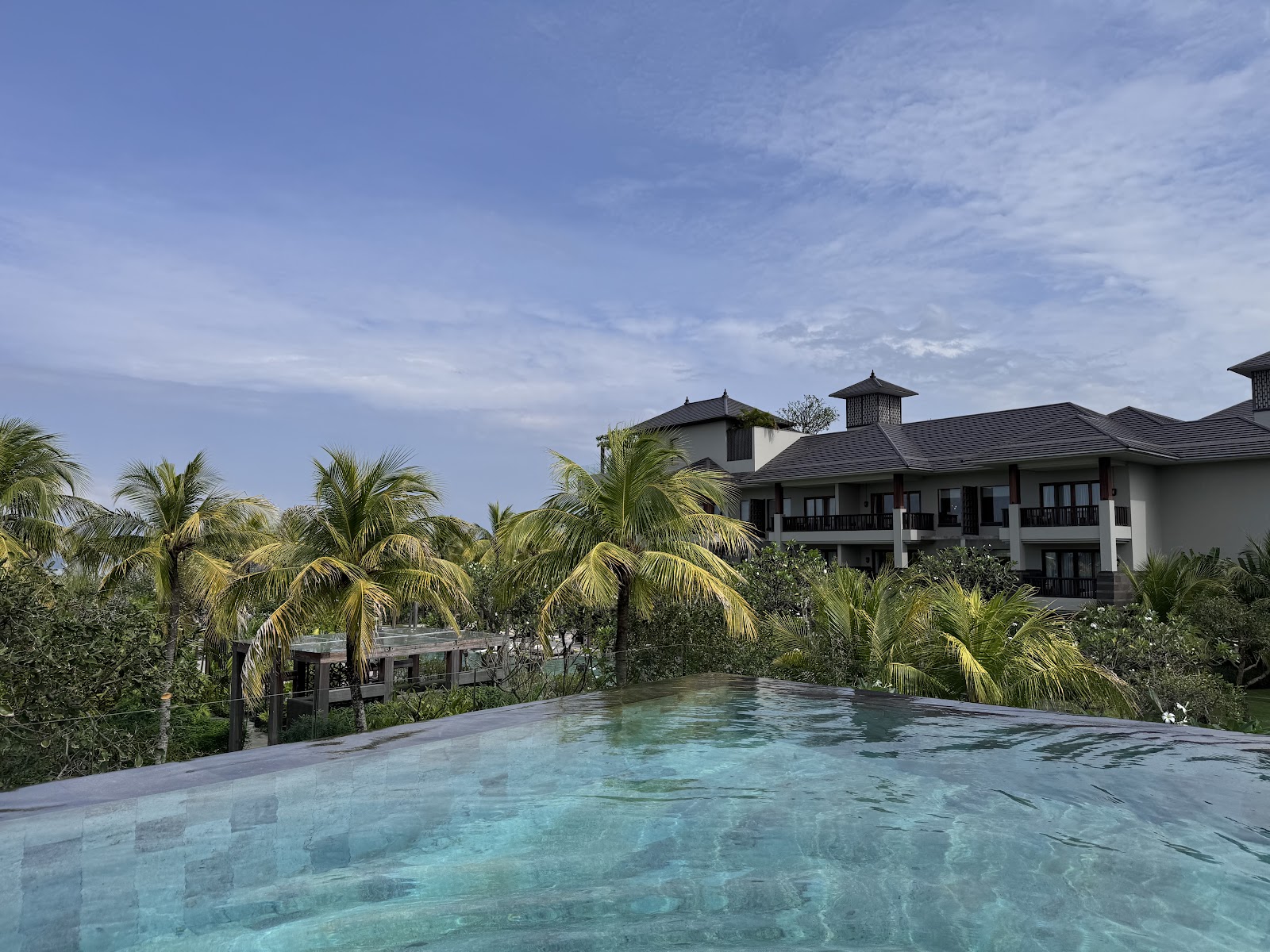 Beachfront pool surrounded by palms at Regent Bali Canggu
